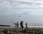 ｜ディリ海岸で網を引く漁師とアタウロ島